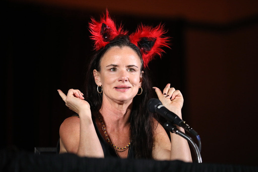 Juliette Lewis, wearing a red, weathered hairband and addressing the audience at an event.