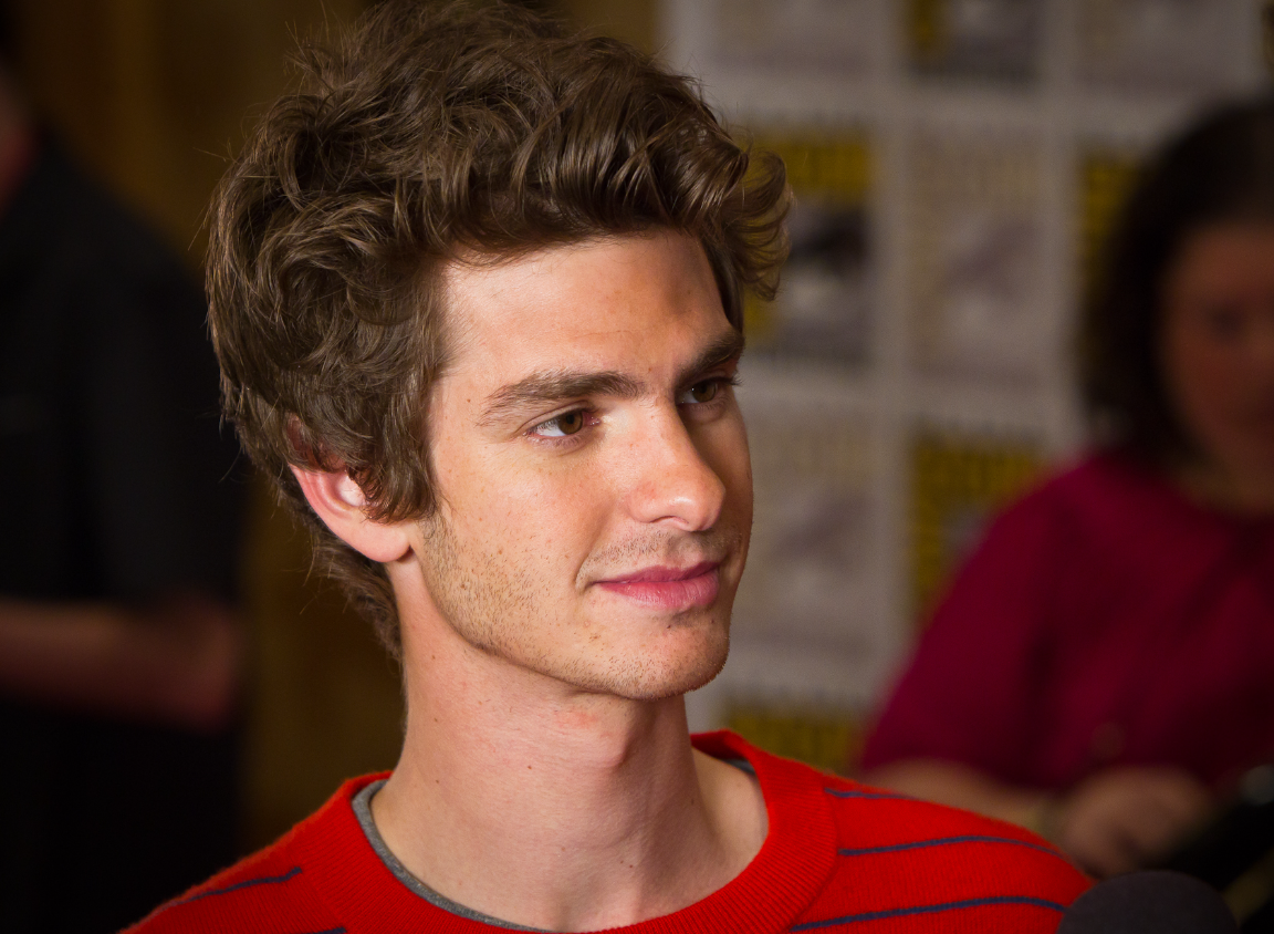 Andrew Garfield is wearing a red shirt and he is looking towards the right side