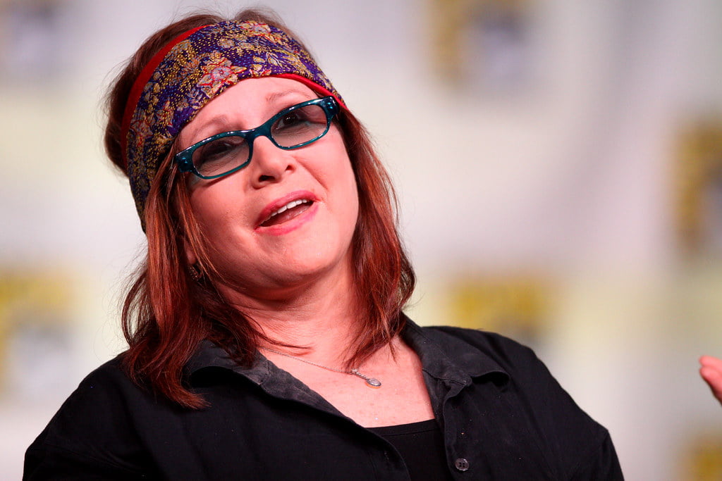 Carrie Fisher in a black dress and glasses, wearing a bandana 