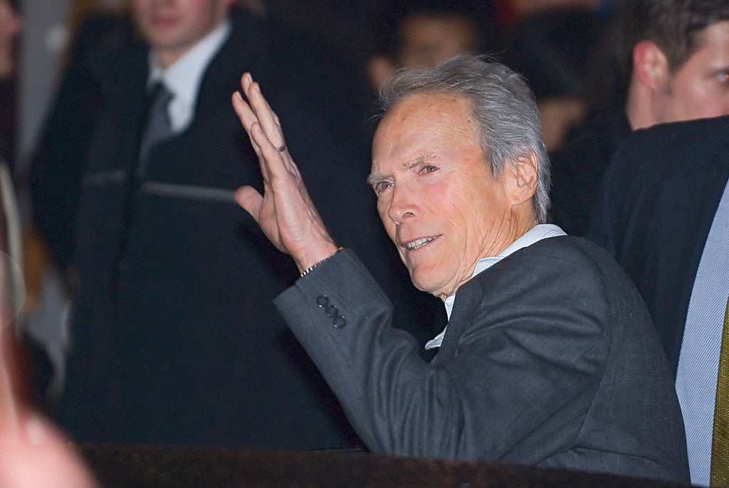 Clint Eastwood wearing a suit appears to be waving at paps.