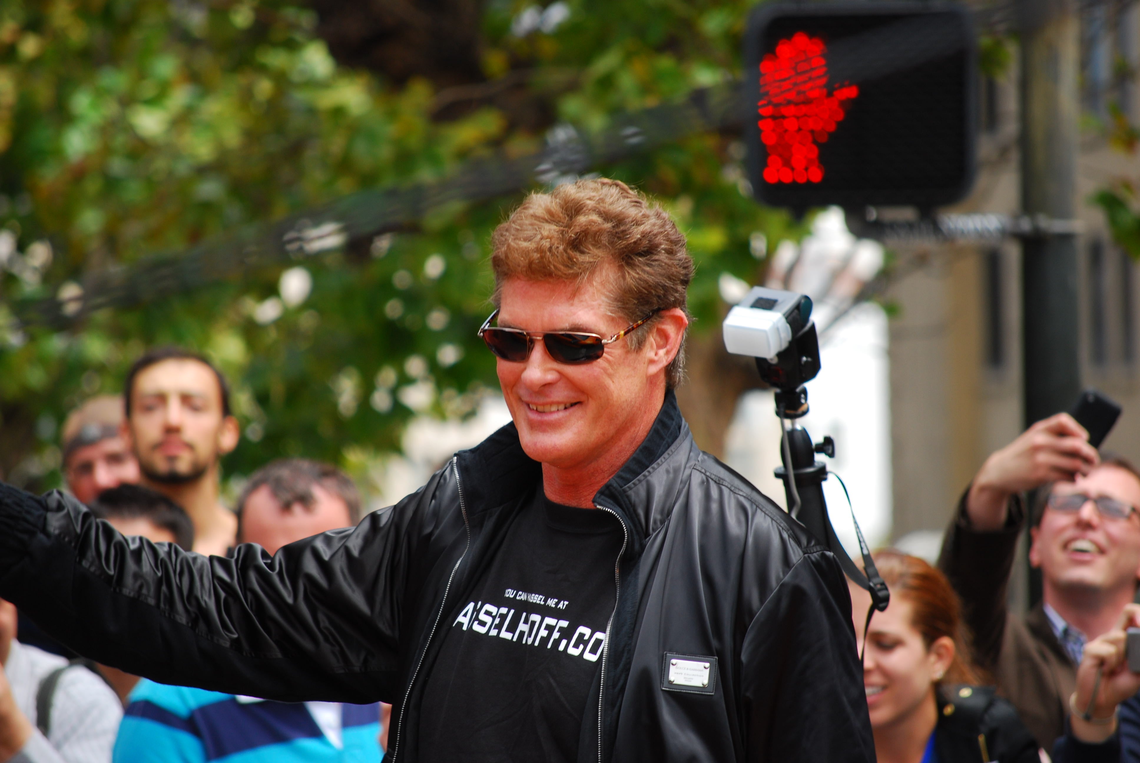 David Hasselhoff smiling and waving at fans while walking down the street.