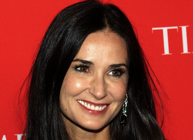 Demi Moore is looking at the camera and smiling.