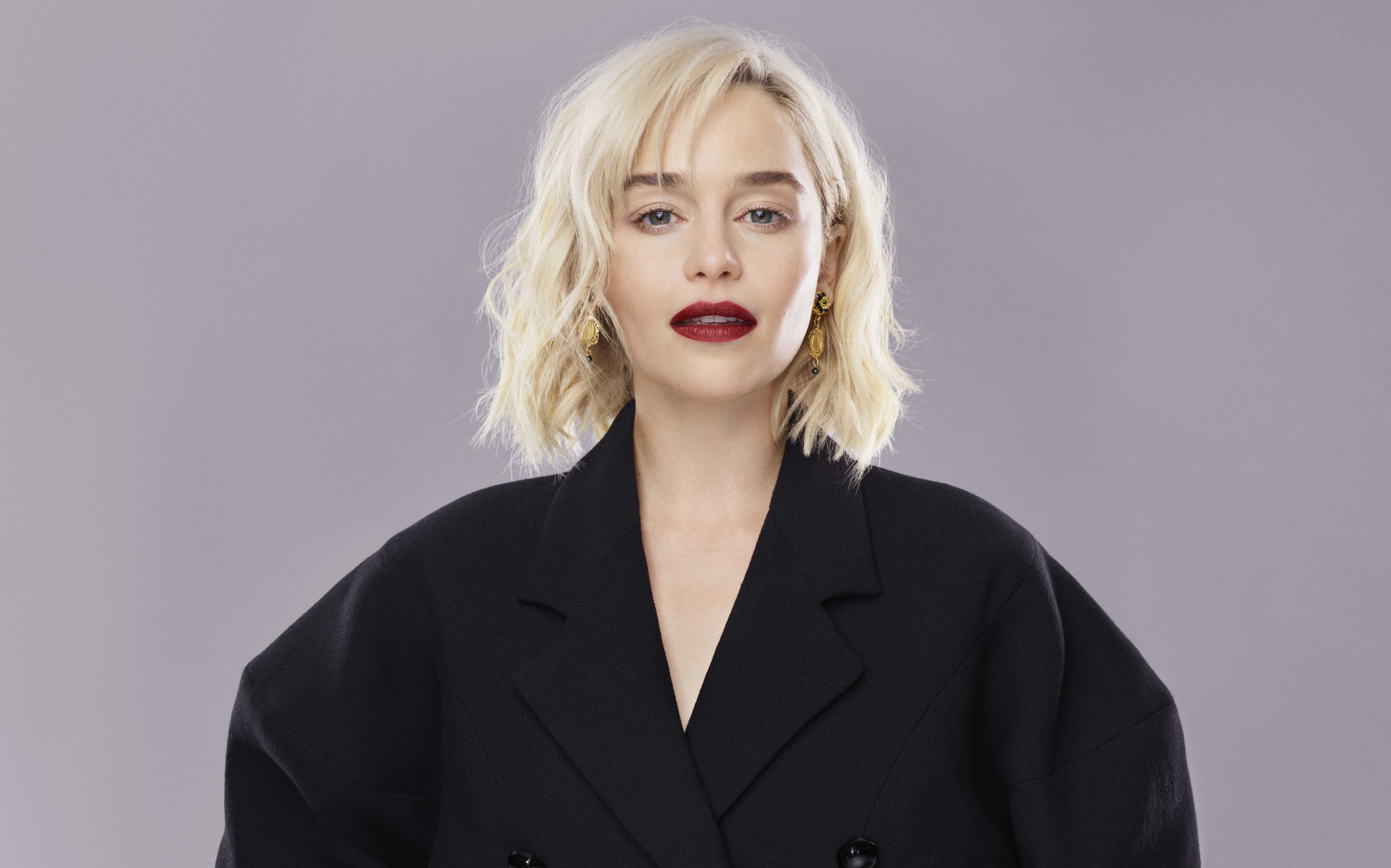 Emilia Clark in an oversized black suit looking at the camera