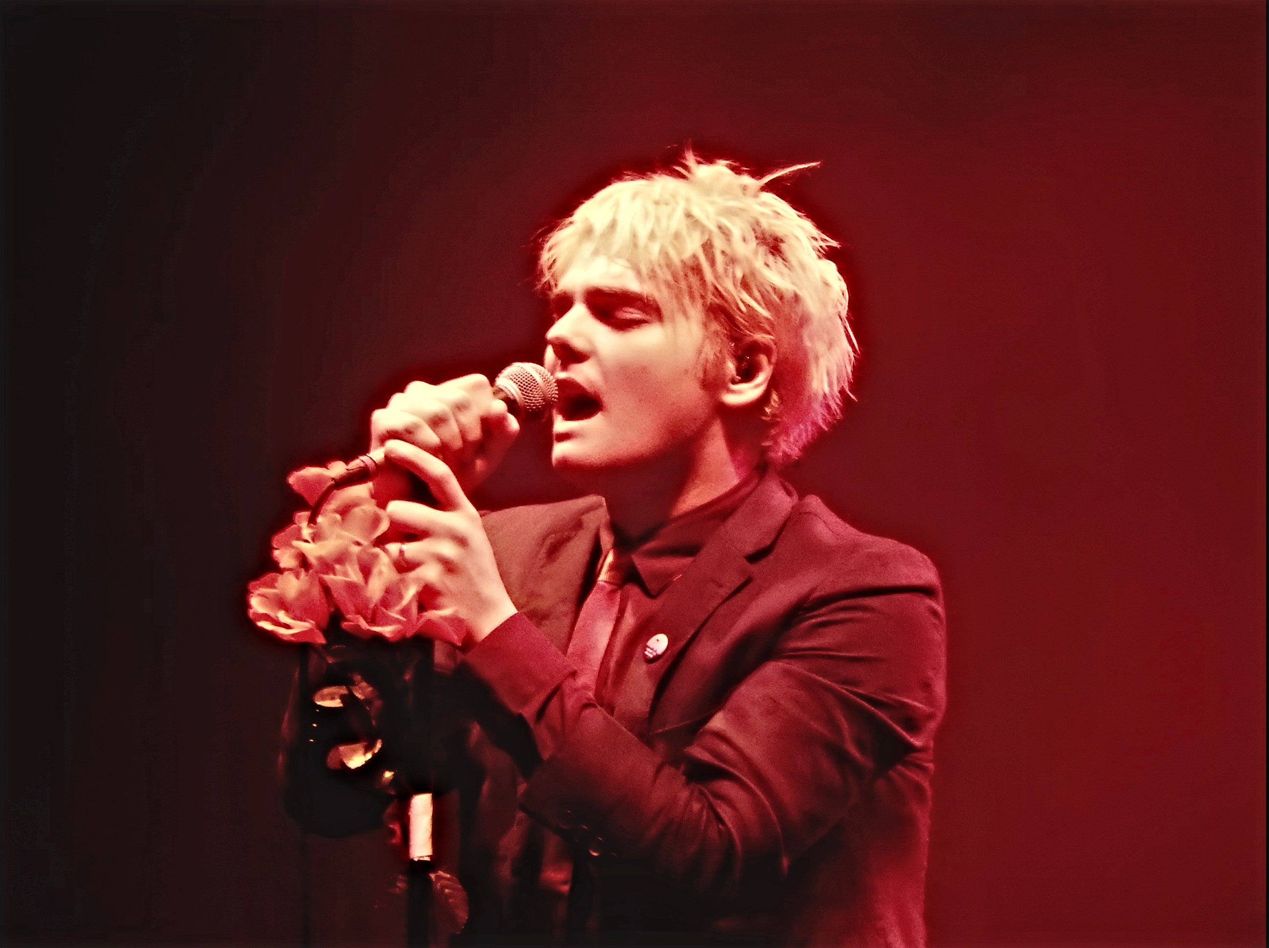 Gerard Way with a microphone in his hand singing on the stage