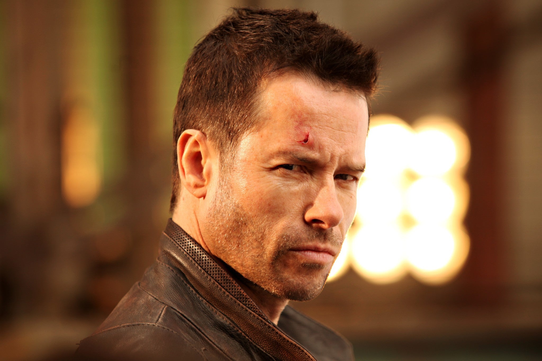 Guy Pearce with a cut on his forehead, looking at the camera with a serious expression.