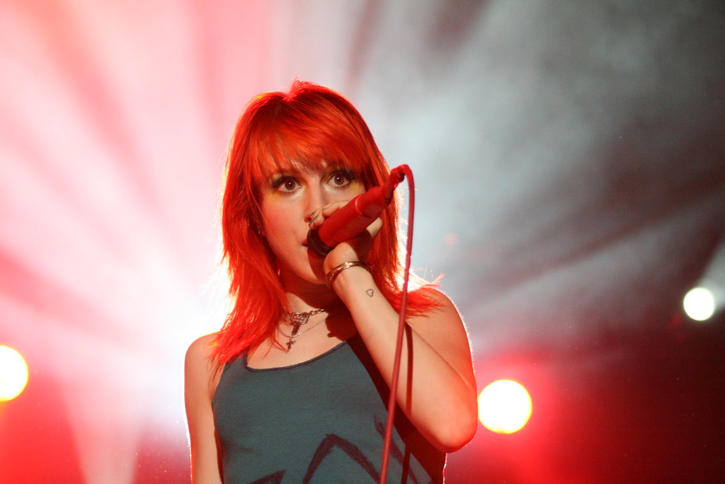 Hayley holding a mic in one hand and singing