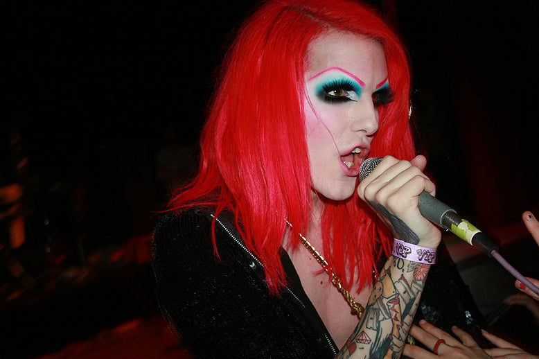 Jeffree Star has red hair and is holding a microphone in their hand