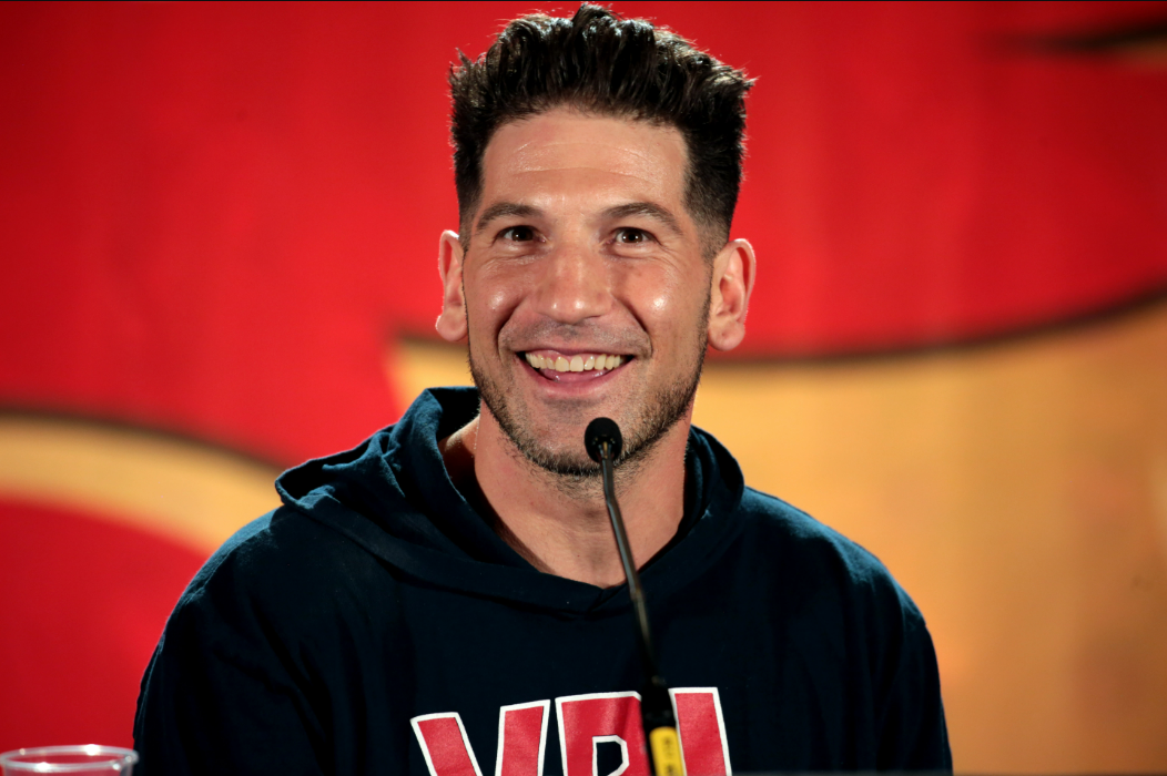 Jon Bernthal wearing a black hoodie at a press conference.