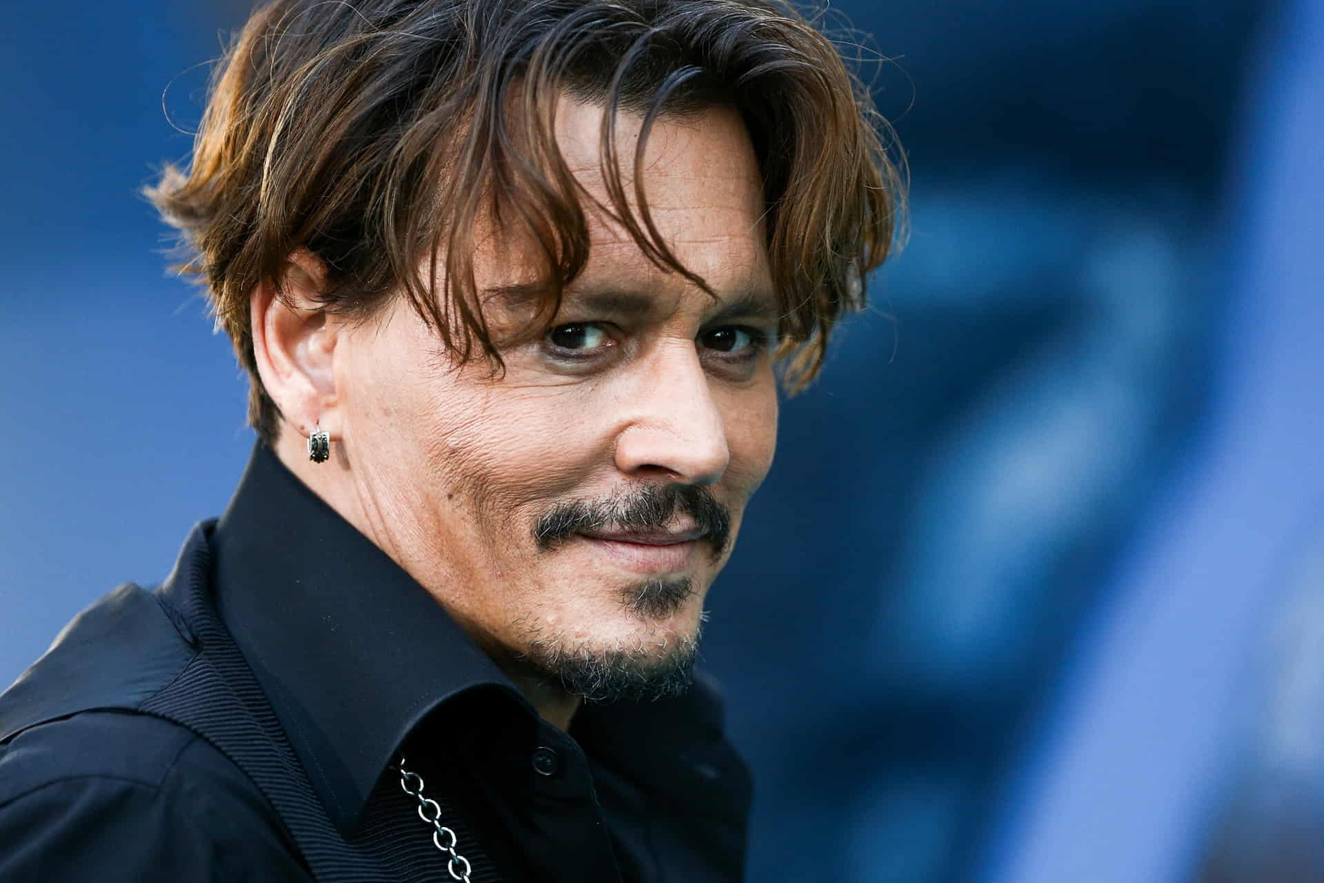 Jonny Depp in a black shirt, smiling while looking into the camera