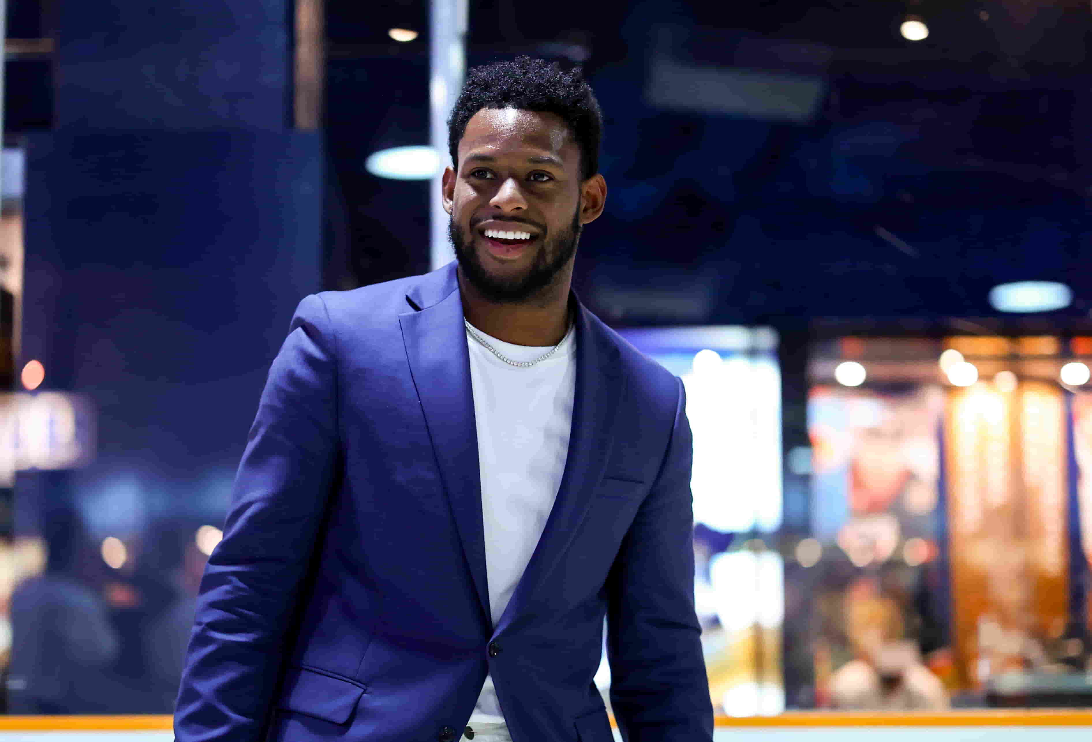 Juju wearing a blue suit on a white t-shirt and smiling.