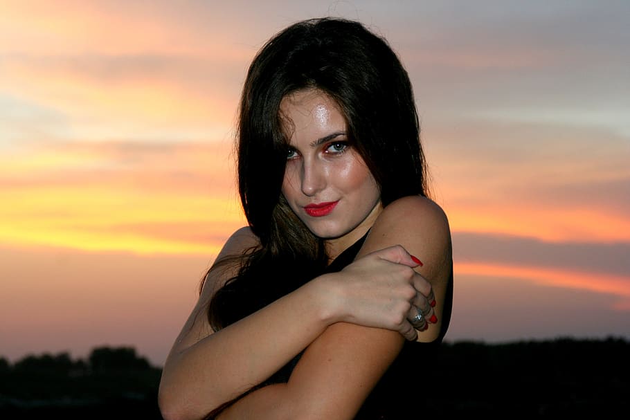 Juliette Lewis is holding her hands together and smiling for a photo with the sunset behind her