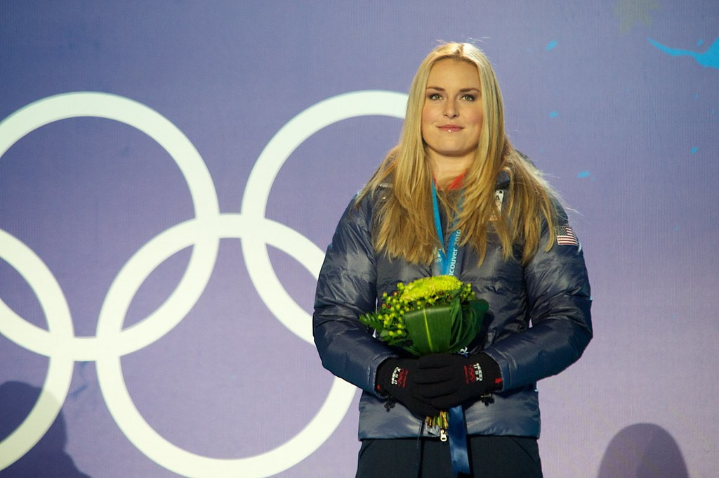 Lindsey holding a bouquet of flowers with Olympic rings in the background.