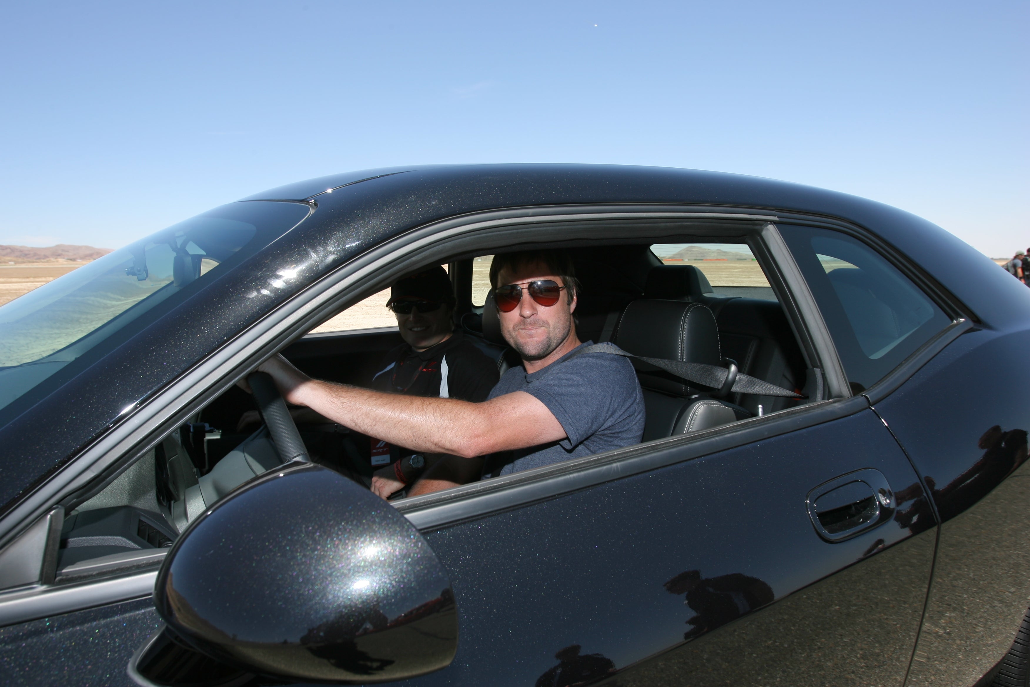 Luke Wilson driving a car outdoors.