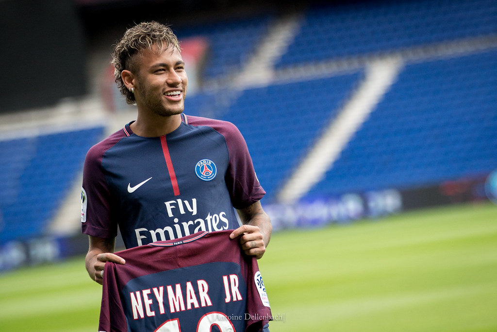 Neymar on the football court with his jersey in his hand.