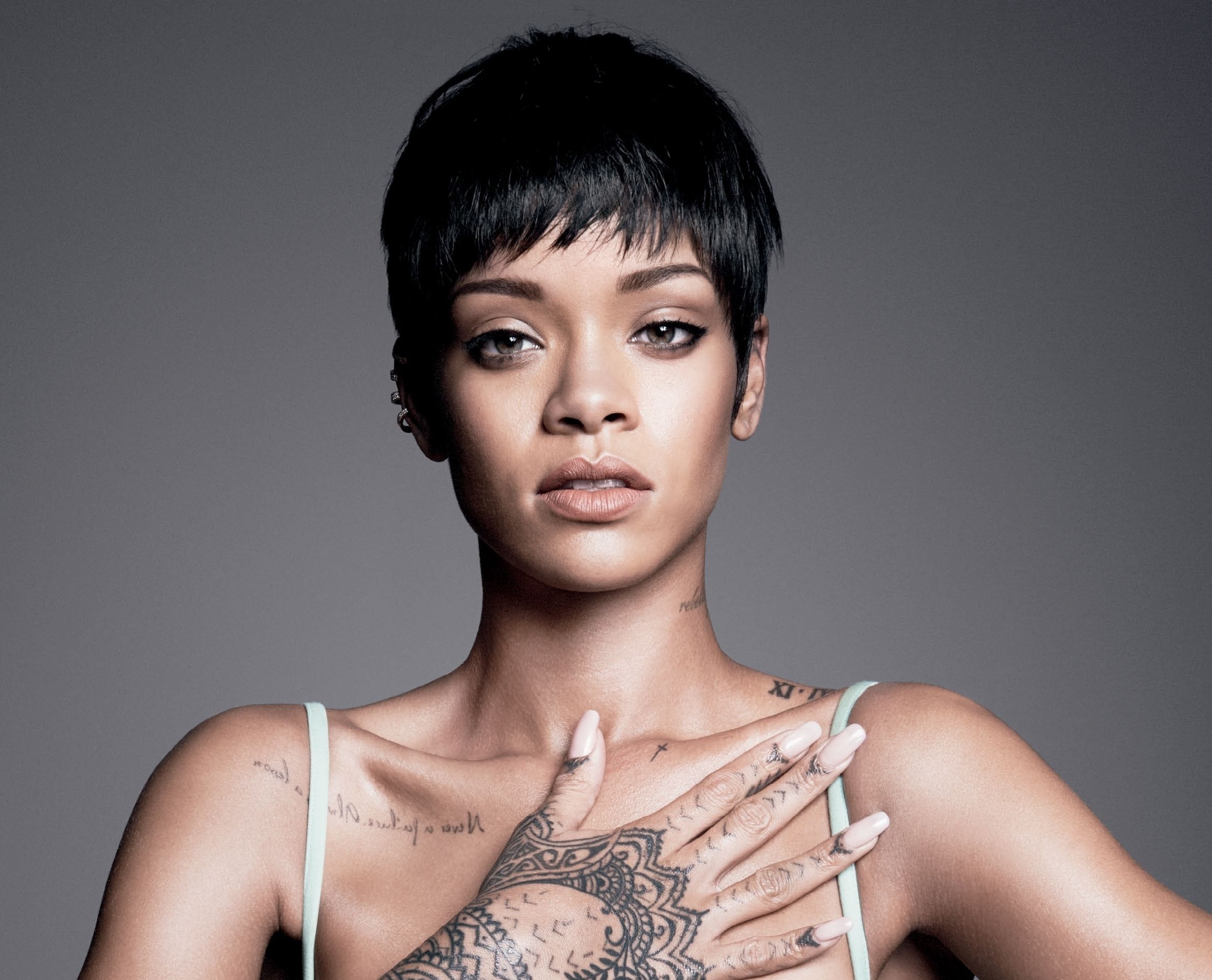 Rihanna with tattoos on her neck, hand, shoulder, and chest.