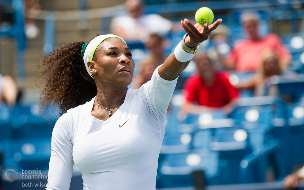 Serena in tennis outfit, holding tennis ball is her left hand.