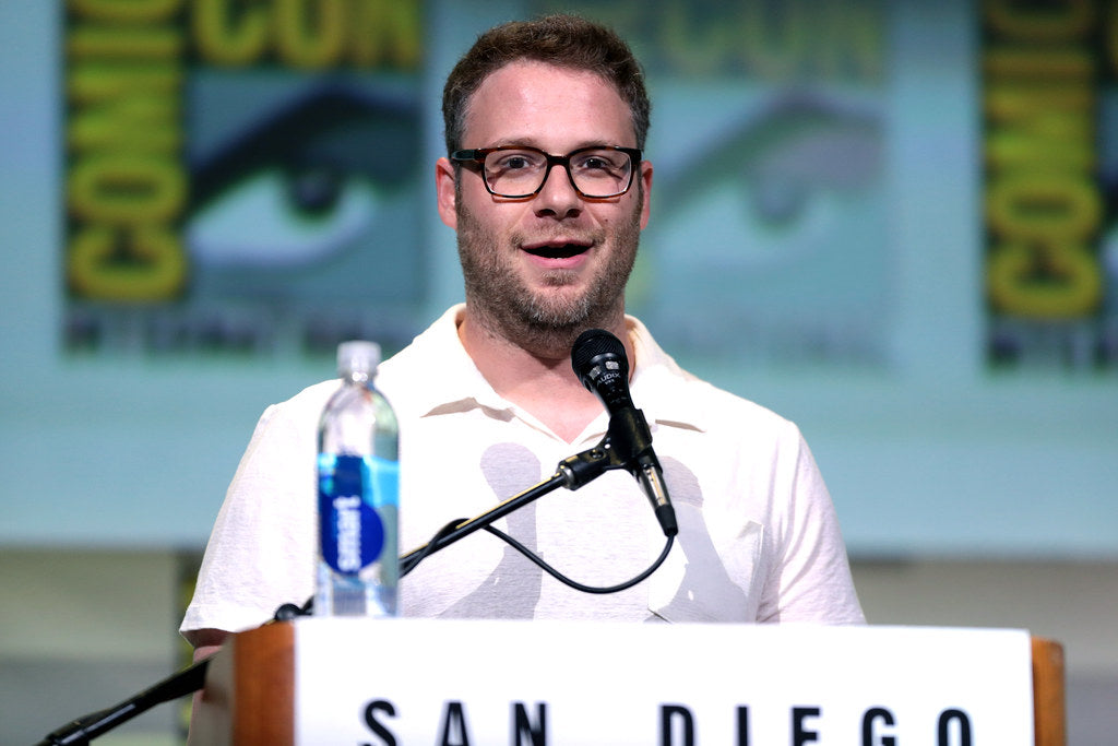 Seth Rogen wearing a white polo shirt addressing the crowd at a comicon