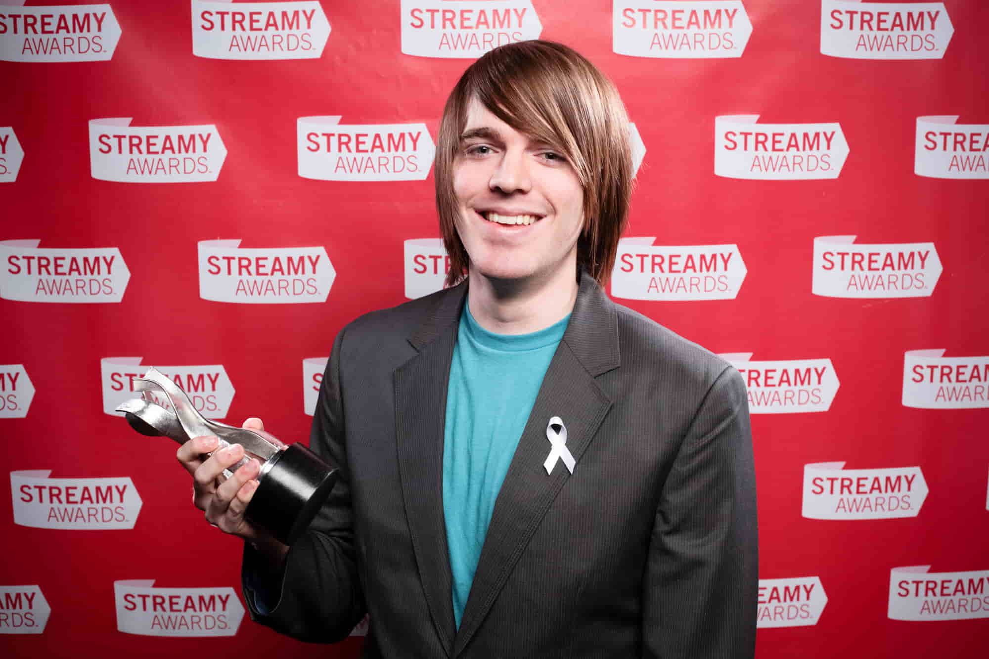 Shane Dawson at Streamy Awards, holding one of his awards and smiling at the camera.