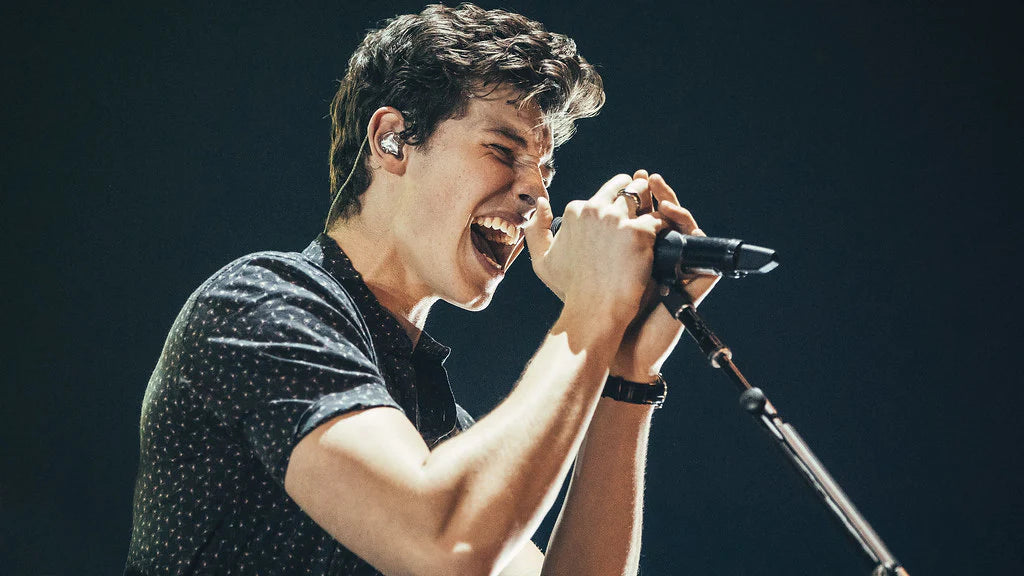 Shawn mendes holding a mic and singing. 