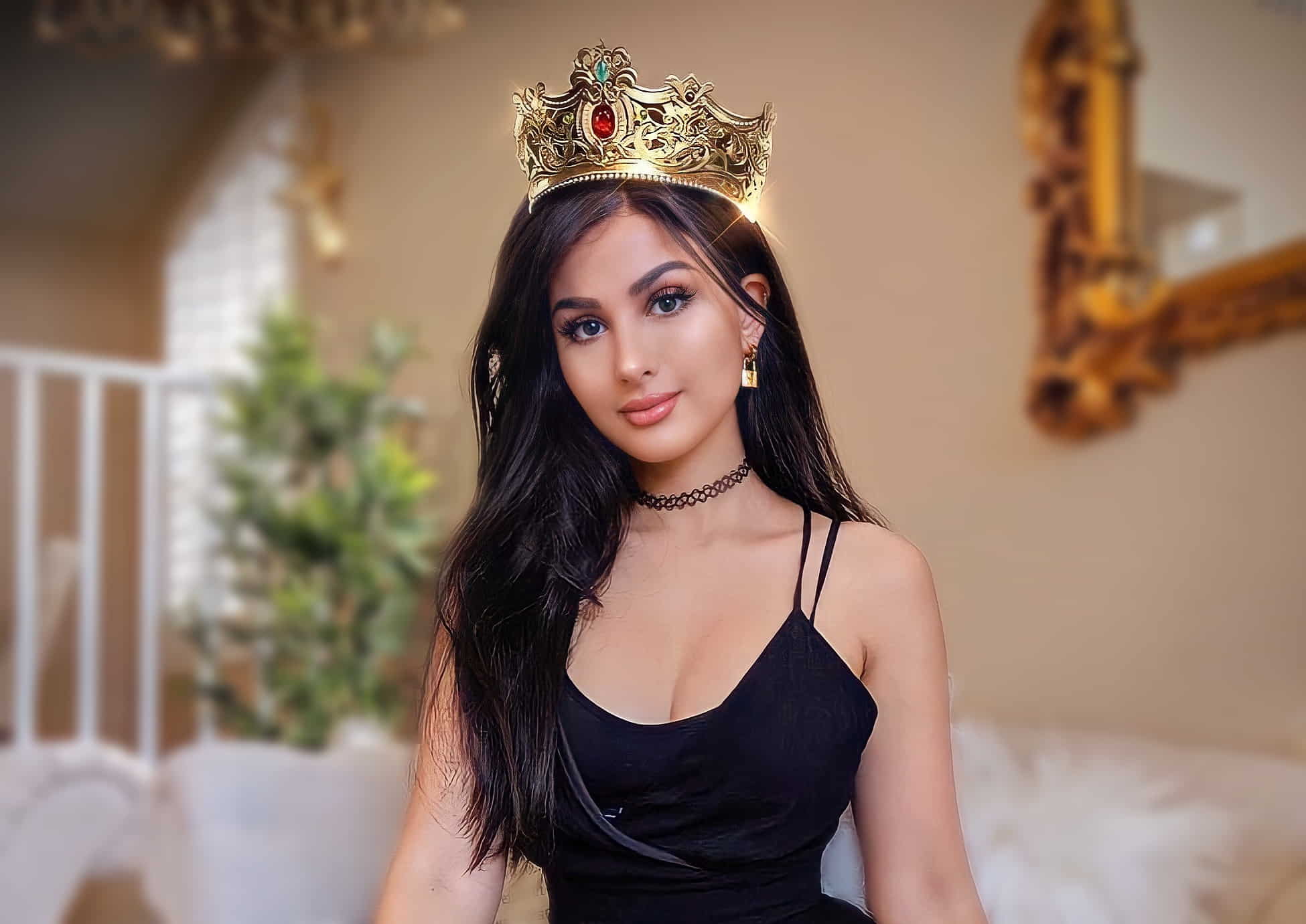 Sssniperwolf wearing a crown as part of a fashion shoot. She is dressed in fashionable clothing and is showcasing long hair.