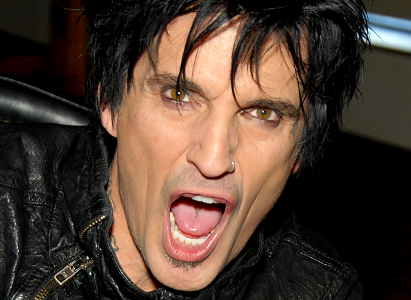 Tommy Lee is shouting with his mouth wide open as he looks at the camera