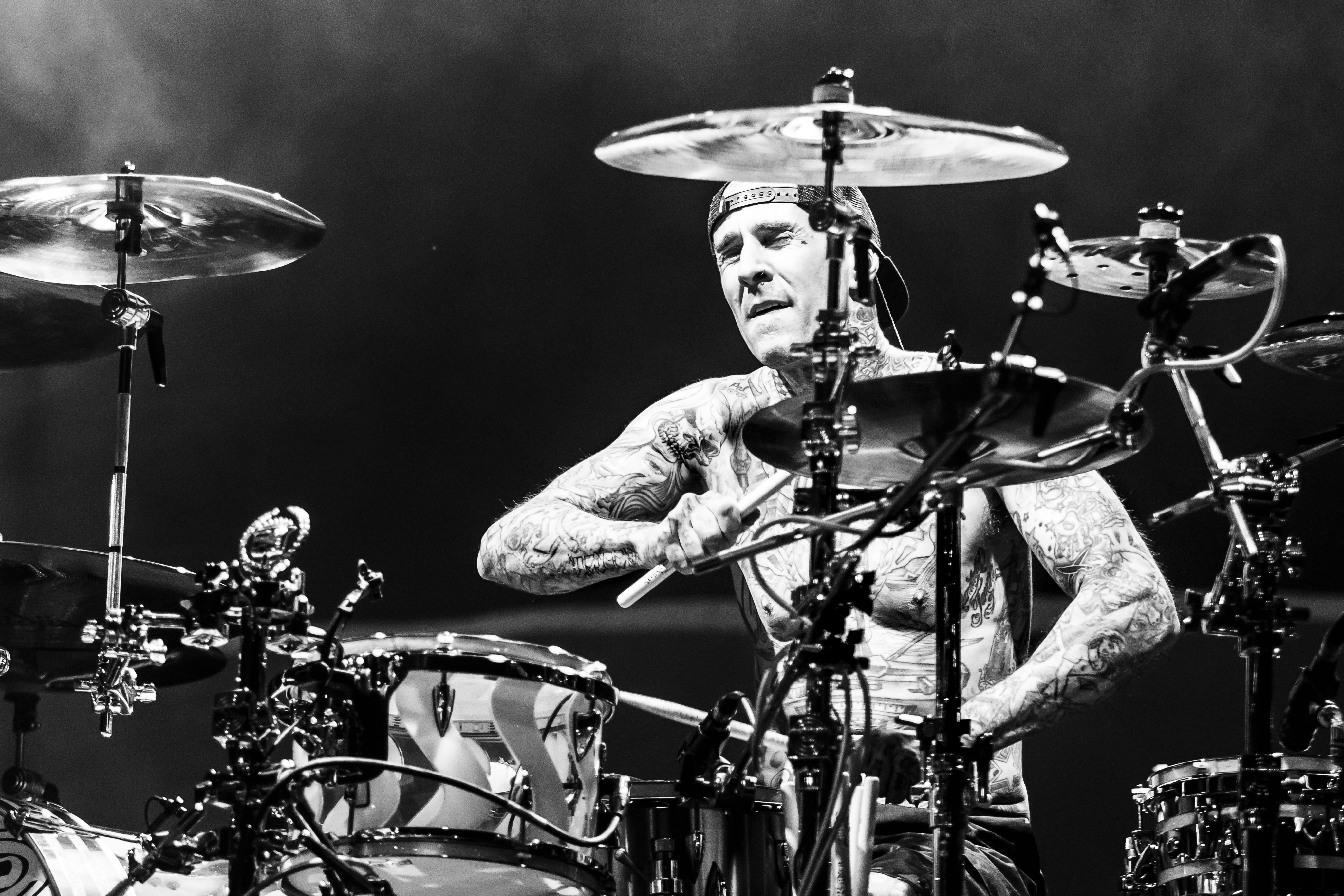 Travis Barker, drummer for Blink-182, is performing on stage with his shirt off.