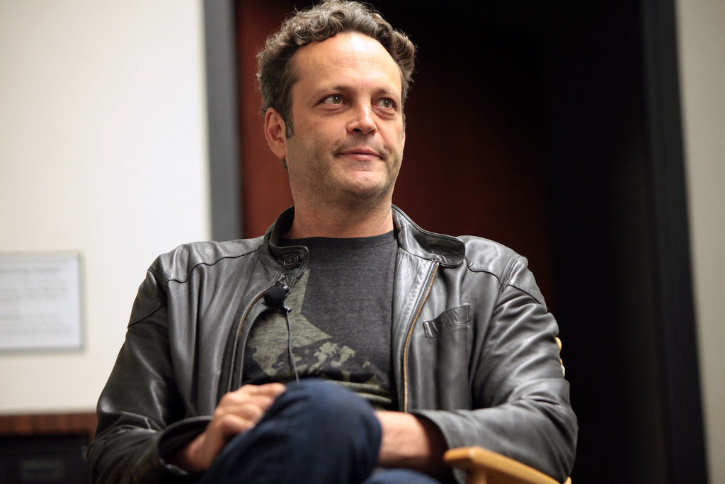 Vince Vaughn is sitting in a chair and wearing a black leather jacket.