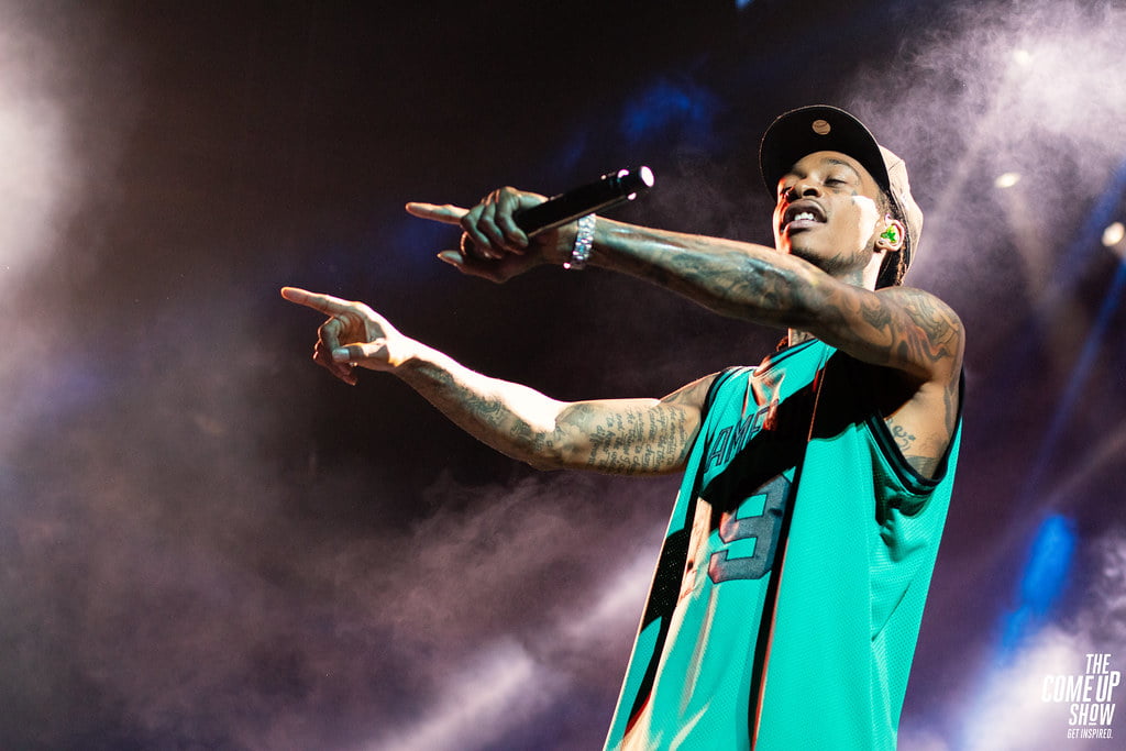 Wiz Khalifa in green t-shirt, pointing towards the audience while performing at his concert