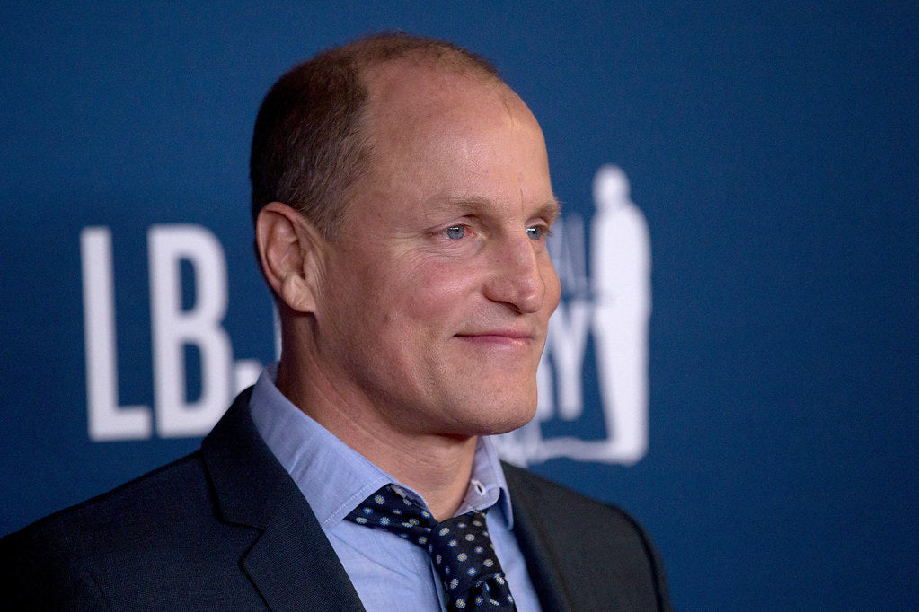 Woody Harrelson in a grey suit at a movie event
