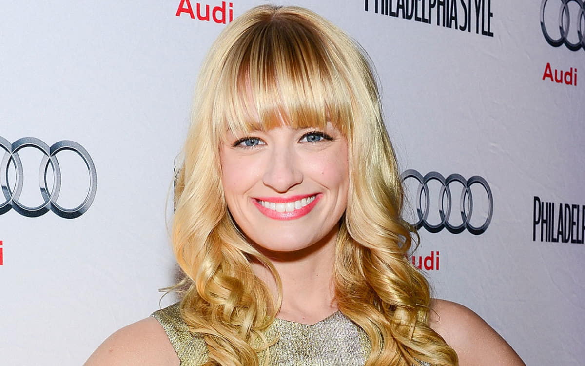 Beth Behrs ina shimmery dress, looking into the camera and smiling