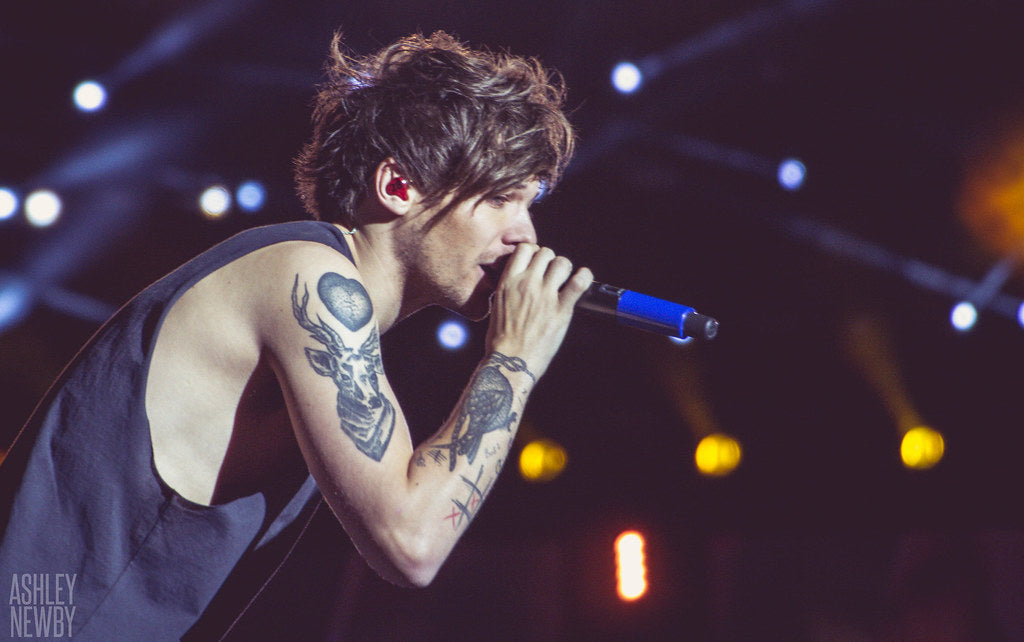 Louis Tomlinson at his concert, holding a mic and singing.